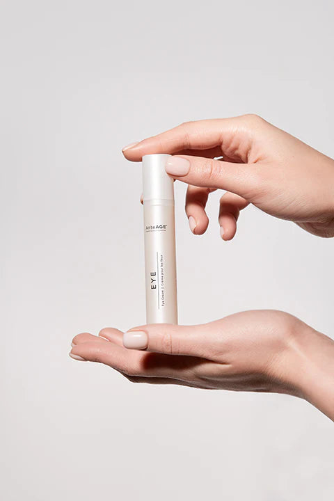 Hand holding a skincare product against a plain background